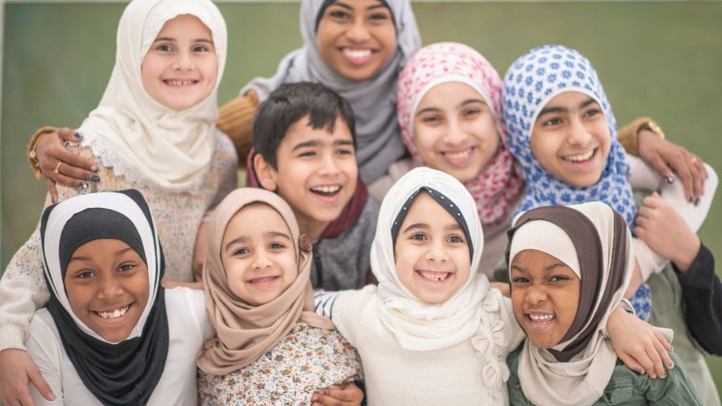 1 woman, with lots of small kids around her smiling