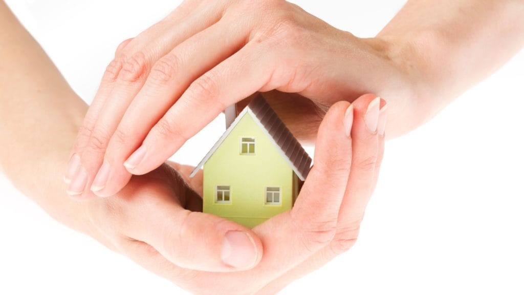 hand over a toy house, covering it, like protection