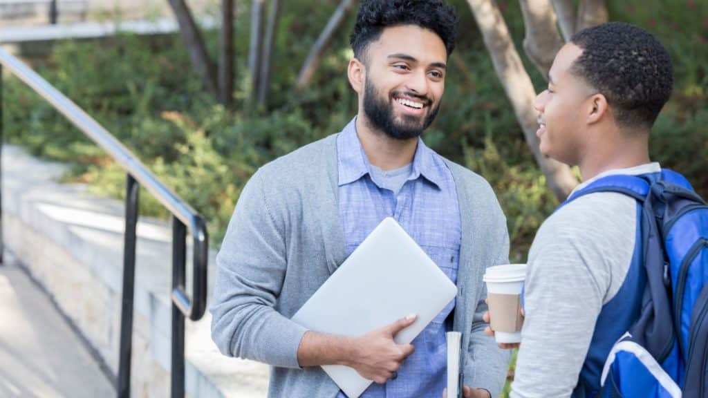 man smiling talking to what looks like a younger man