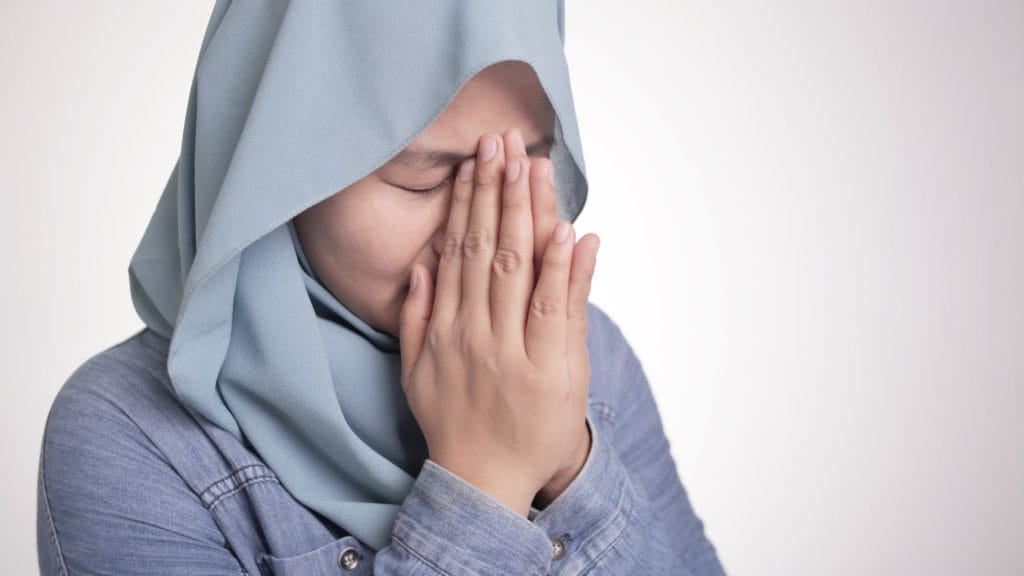 woman holding her hands together close to her face