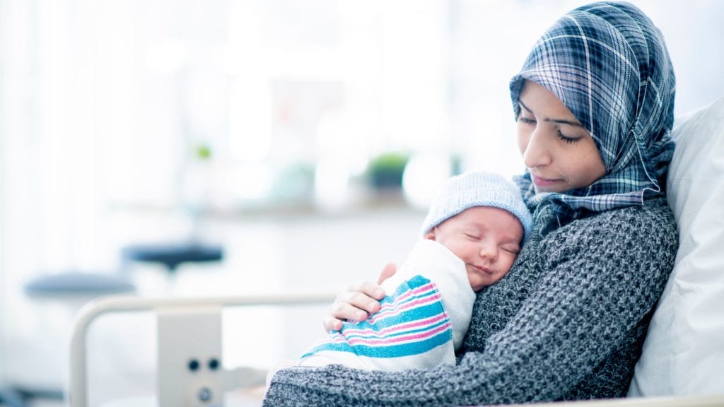 woman holding calm smiling, sleeping baby in her arms