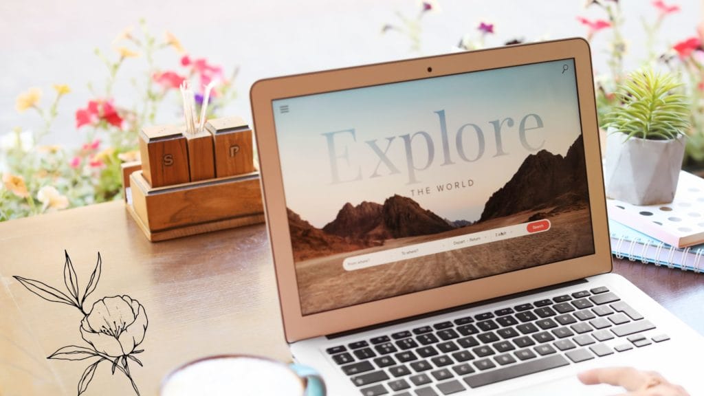 A laptop open with a website on screen and some flowers in the background